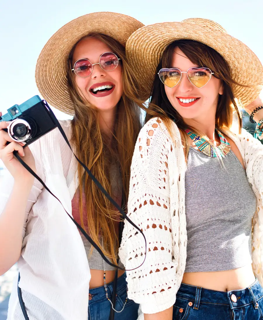 Two stylish young women in summer outfits smiling and enjoying a vacation, representing exclusive deals and special offers.